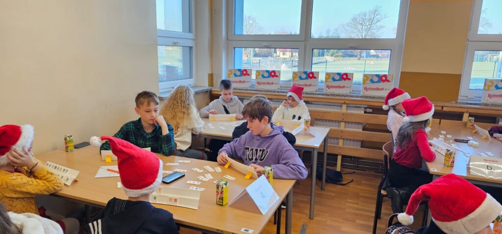 I Międzyszkolny Mikołajkowy Turniej Rummikub. Na zdjęciu uczniowie siedzą przy stolikach i grają w Rummikub.