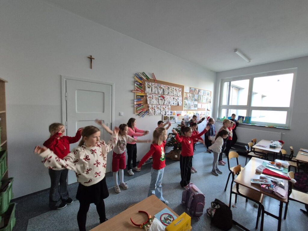 Integracyjny WF online - Tajemnica Świątecznej Fabryki. Na zdjęciu uczniowie wykonują ćwiczenia rękami według tego, co widzą na ekranie.