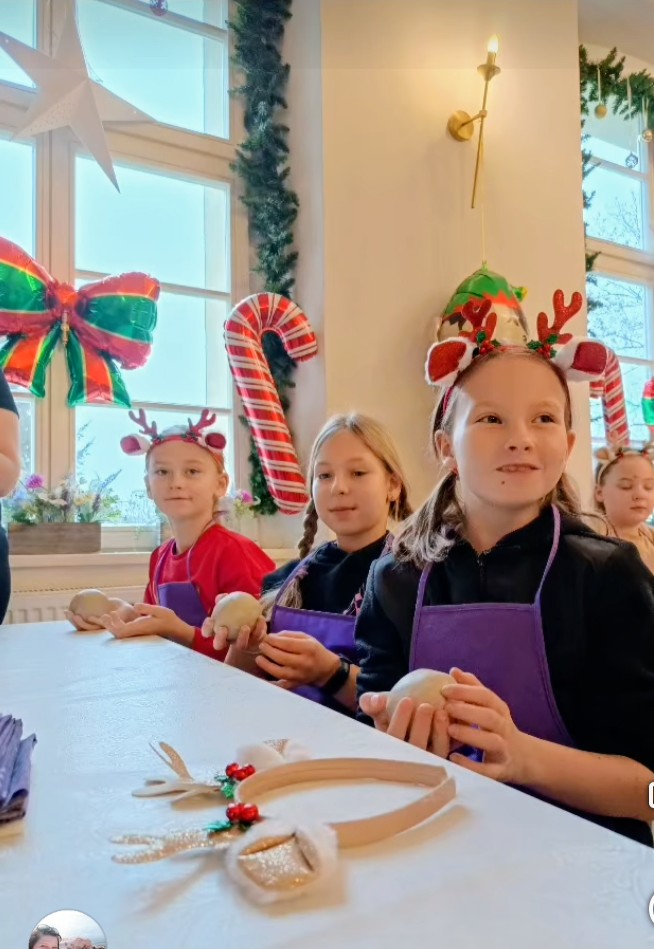 Świąteczne warsztaty ceramiczne w Chichach. Na zdjęciu uczennice z rożnymi ozdobami świątecznymi na głowach trzymają w ręce glinę.