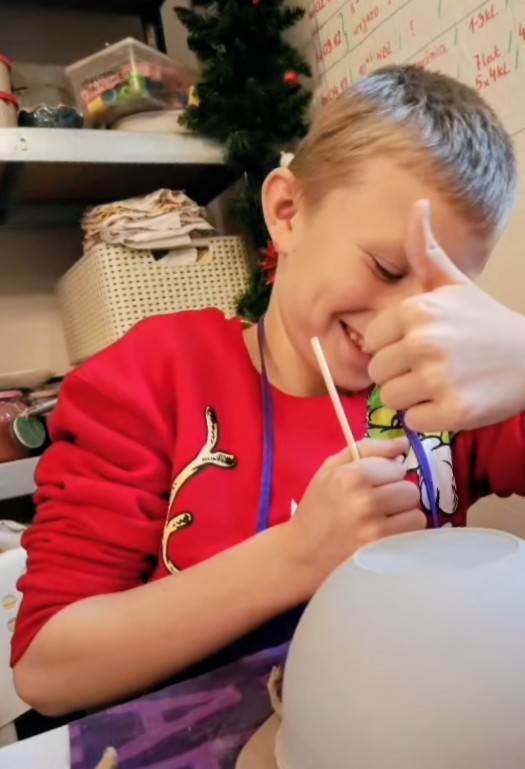 Świąteczne warsztaty ceramiczne w Chichach. Na zdjęciu uczeń bierze udział w warsztatach, odrysowuje od miski kształt na swojej glinie.