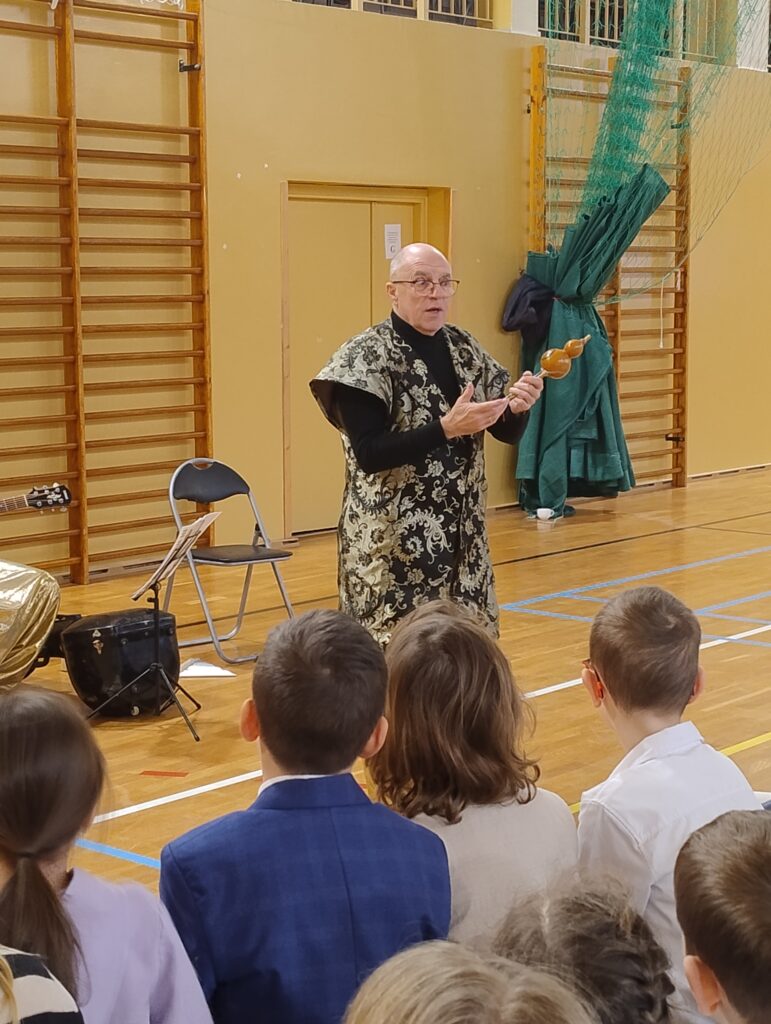 Prowadzący ubrany w orientalną szatę prezentuje dzieciom hulusi – drewniany instrument kształtem przypominający gruszkę.