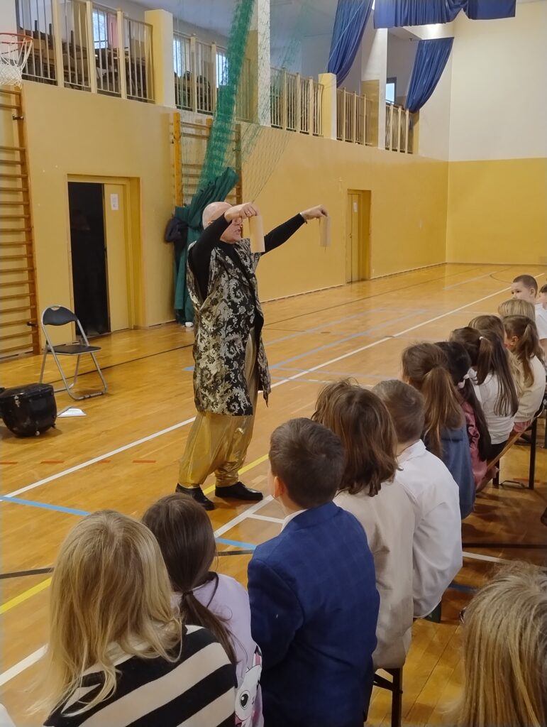 Prowadzący w orientalnej szacie prezentuje dzieciom wietnamskie dzwonki kushi – instrumenty wyglądają jak drewniane tuby. W ich środkach znajdują się dzwoneczki, które wydobywają z siebie delikatne i magiczne dźwięki.