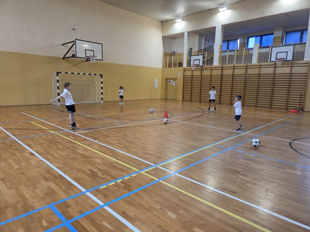 Program "Aktywna Szkoła do Kwadratu". Na zdjęciu chłopcy grają w piłkę nożną na sali gimnastycznej.