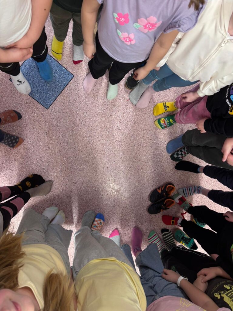 Na zdjęciu stopy uczniów z klasy 2b w kolorowych skarpetkach podczas akcji
Światowy Dzień Zespołu Downa, znany również jako Dzień Kolorowej Skarpetki.