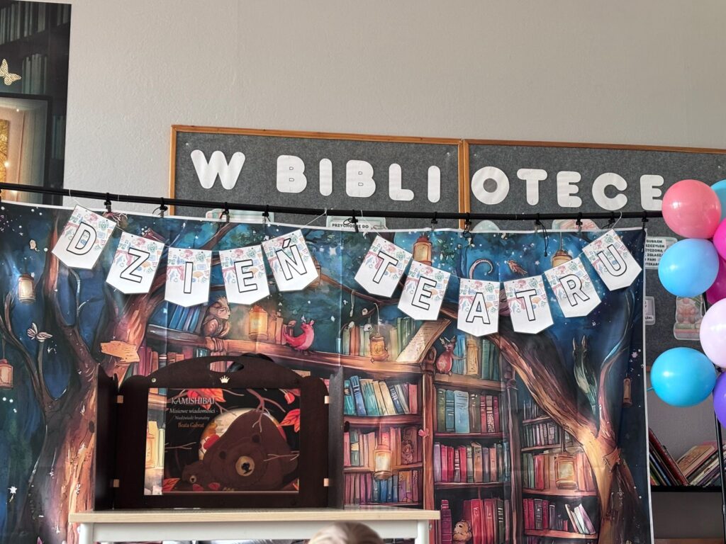 Zdjęcie przedtswia girlandę- Dzień Teatru wiszącą na tle plakatu z ksiązkami . G