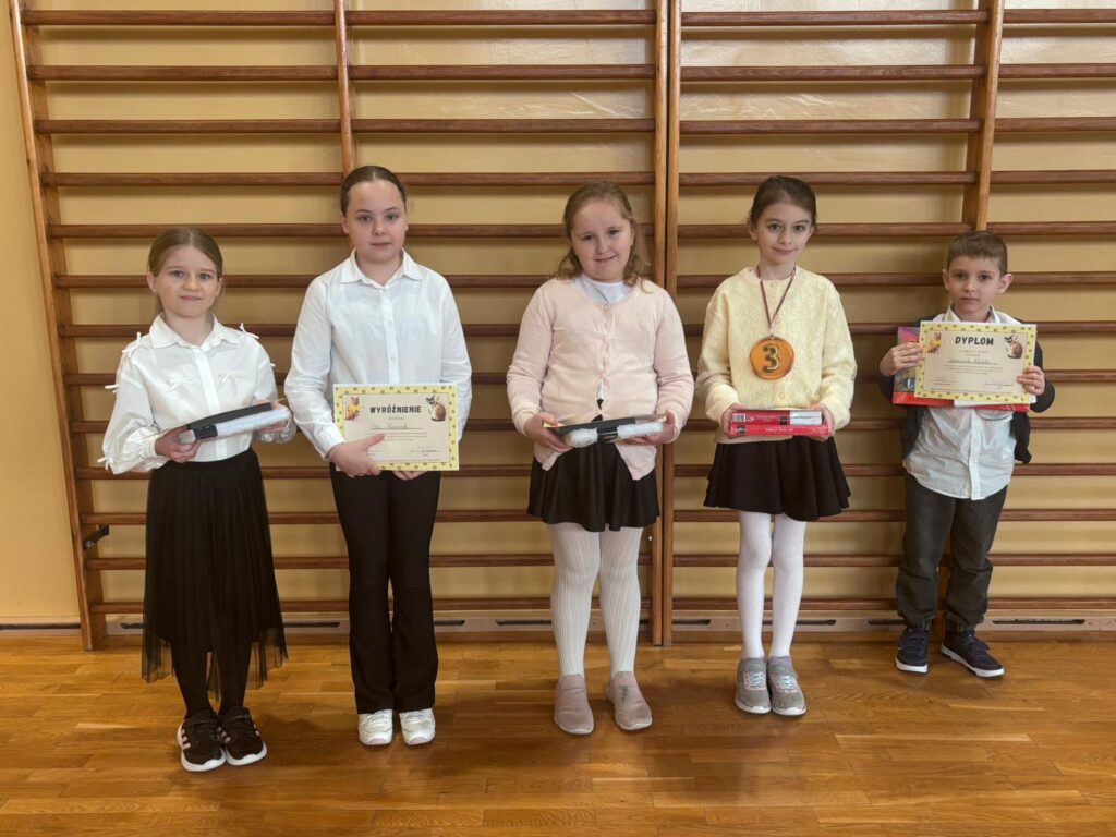 Zdjęcie przedstawia laureatów konkursu SUPER-KOT – cztery dziewczynki i jednego chłopca. Uczniowie stoją w jednym rzędzie, w rękach trzymają wygrane nagrody oraz dyplomy.