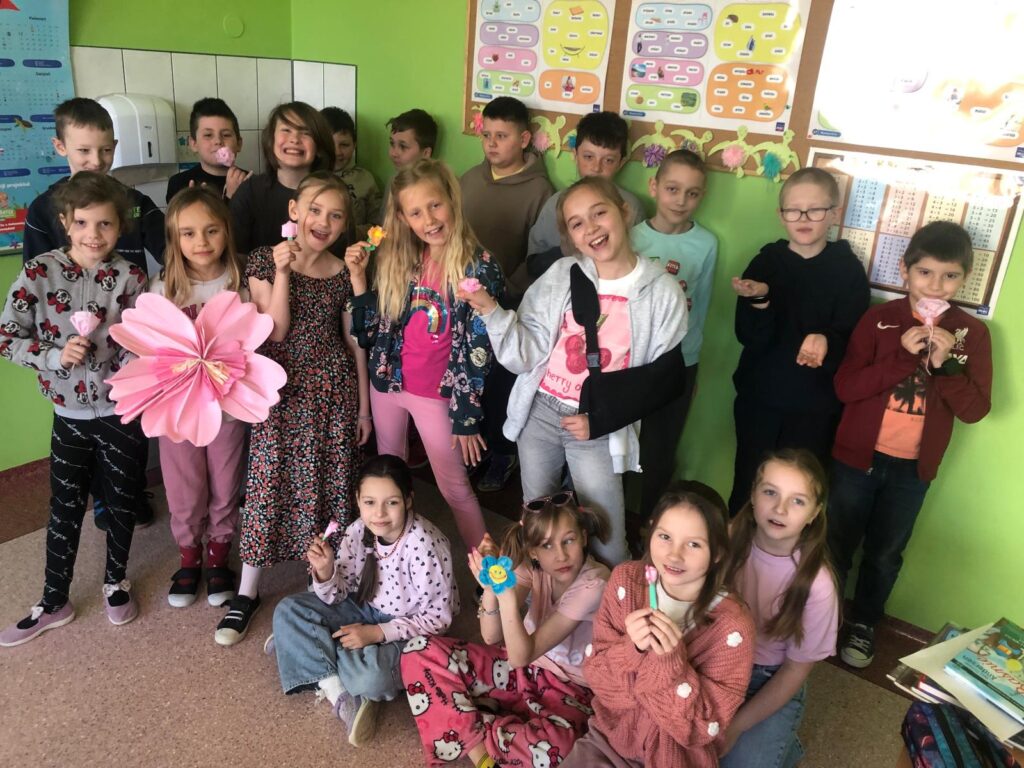 djęcie przedstawia uczniów klasy 3a, którzy pozują w grupie. Na pierwszym planie znajdują się dziewczynki ubrane na różowo, za nimi stoją chłopcy.
