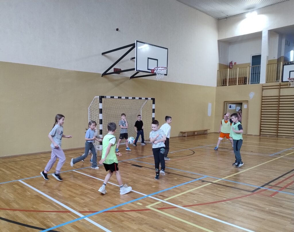 djęcie przedstawia urywek z meczu towarzyskiego pomiędzy drugimi klasami. Akcja rozgrywa się przy jednej z bramek, uczniowie próbują zdobyć gola