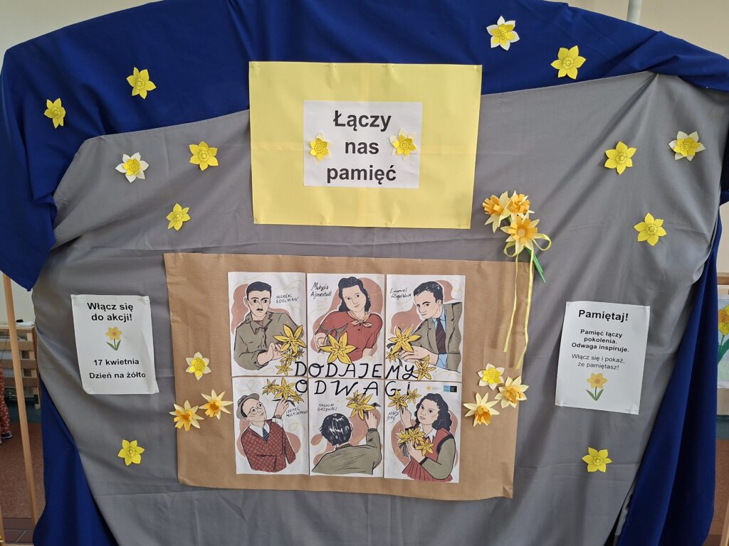 Przedstawia szkolną gazetkę z postaciami biorącymi udział w powstaniu w getcie warszawskim. Na żółtym tle jest napis "Łączy nas pamięć". Wokół gazetki przywieszone są żółte żonkile.