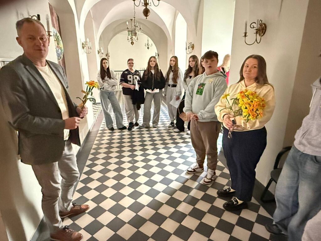 Akcja "Żonkile 2026". Na zdjęciu uczniowie klasy siódmej stoją na korytarzu w pałącu w siedzibie gminy Gaworzyce, po leej stronie stoi pan Wójt, a po prawej wychowawczyni. 