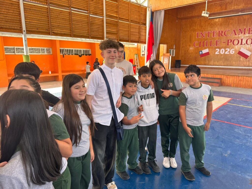 Nasi uczniwoie dotarli do Chile. Na zdjęciu uczniowie z Polski wraz z uczniami z gminy Sierra Gorda ppzują do zdjęcia uśmiechają się. 