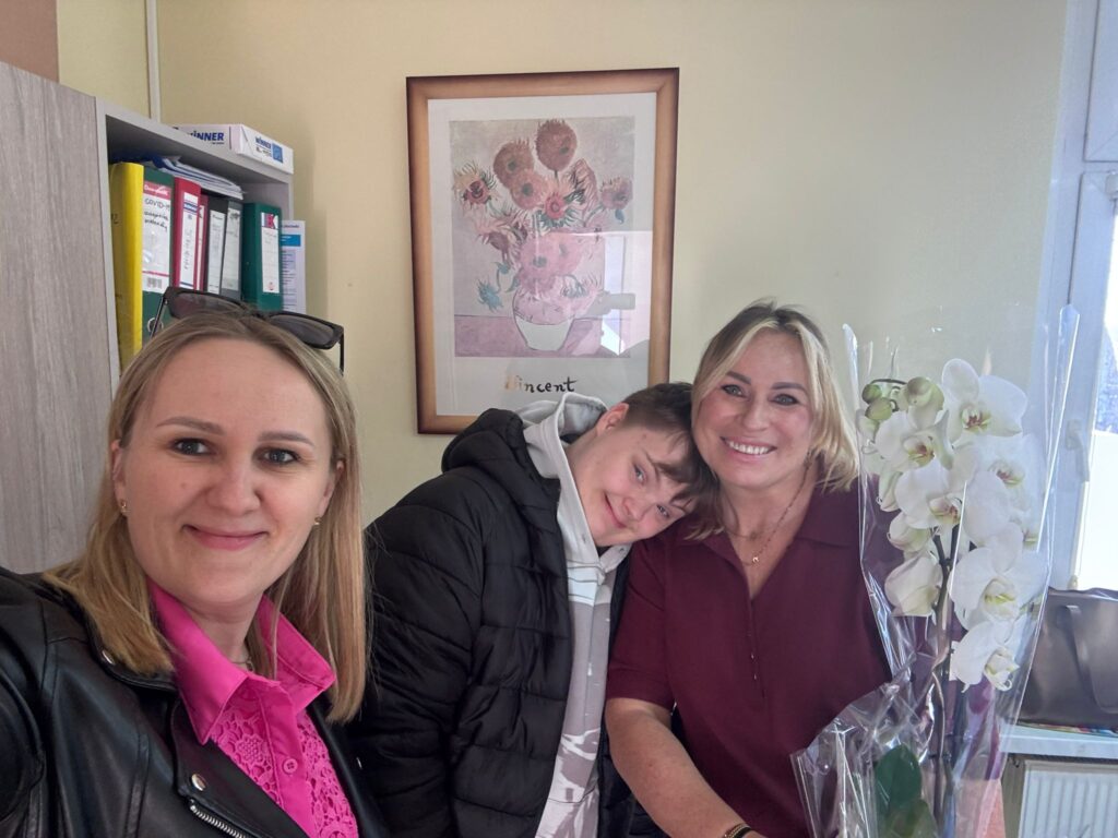 Życzenia z okazji Dnia Służby Zdrowia. Na zdjęciu uczeń wręcza kierowniczce Gminnego Ośrodka Zdrowia kwiat. Przed uczniem stoi także nauczycielka, wszyscy się uśmiechają.