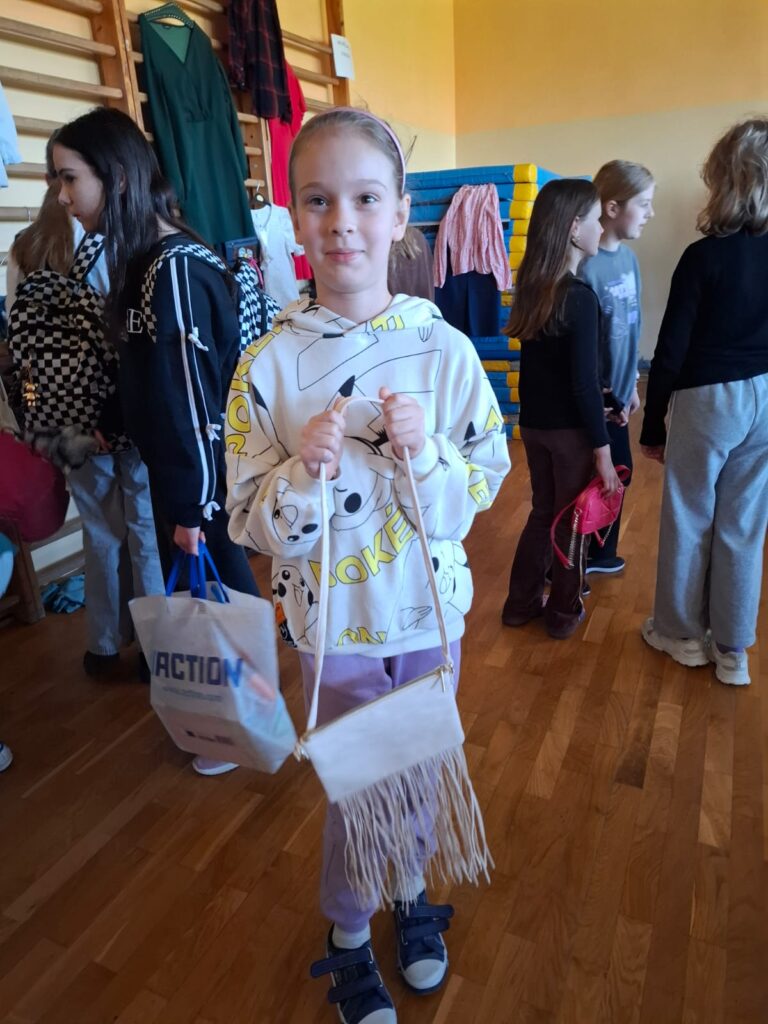 Szafing- Adoptuj ciucha, czyli wielka wymiana ubrań. Na zdjęciu uczennica, która wzięła udział w akcji i zaadoptowała ciucha. Uczennica trzyma w rękach jasną torebkę. 