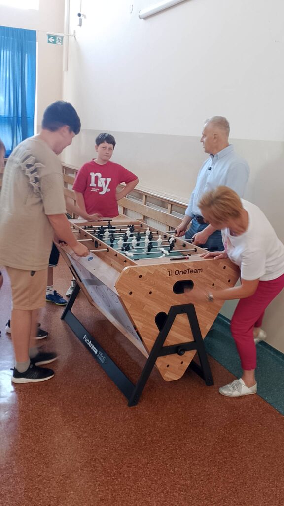 Wizyta Starosty Polkowickiego w naszej szkole. Na zdjęciu Pan Starosta, Pani Dyrekor i trzech uczniów gra w piłkarzyki.