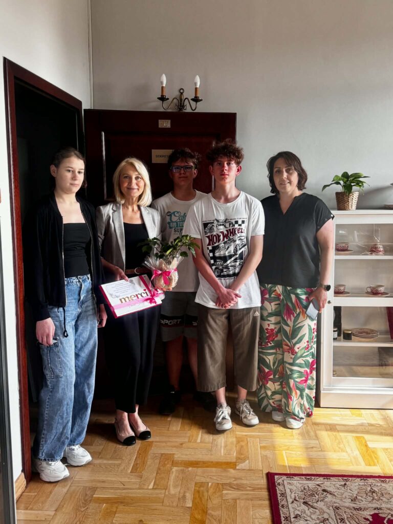 Dzień Samorządu Terytorialnego. Na zdjęciu troje uczniów pozuje do zdjęcia. Z prawj strony uczniów stoi nauczycielka, natomiast druga osoba od lewej strony to pani Zastępca Wójta. 