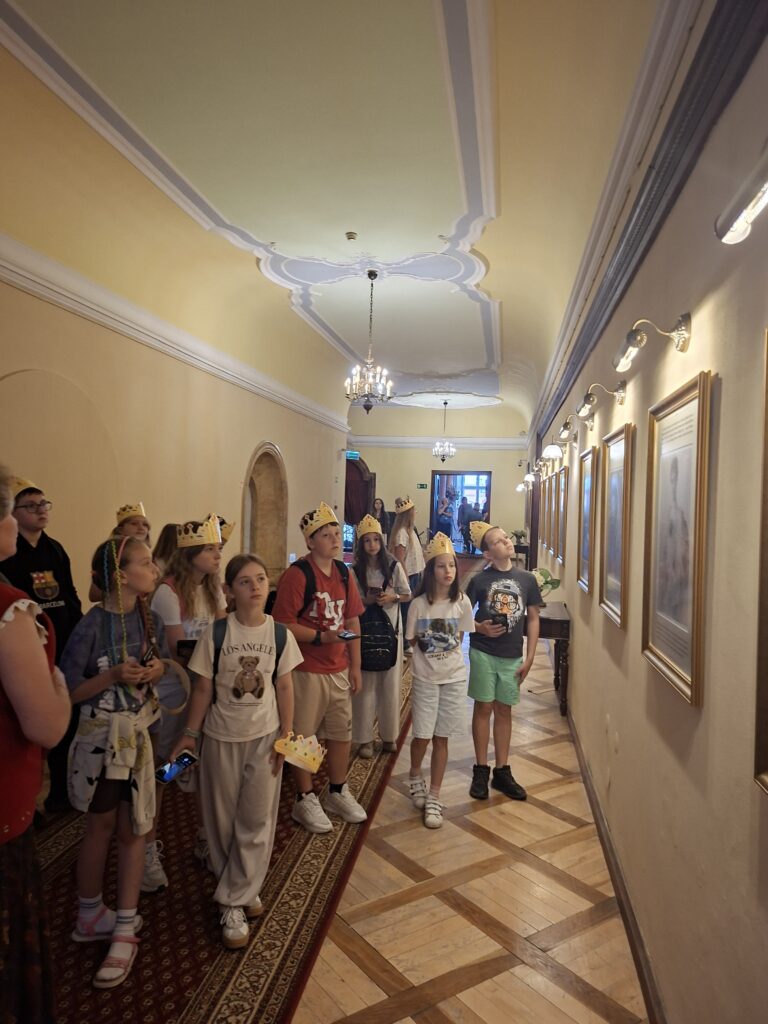Przedstawia stojących uczniów w podłużnym korytarzu zamku podziwiających obrazy przedstawiające księżną Daisy. Podłogę tworzy parkiet na którym jest kolorowy dywan. Sufit jest biało-żółty.