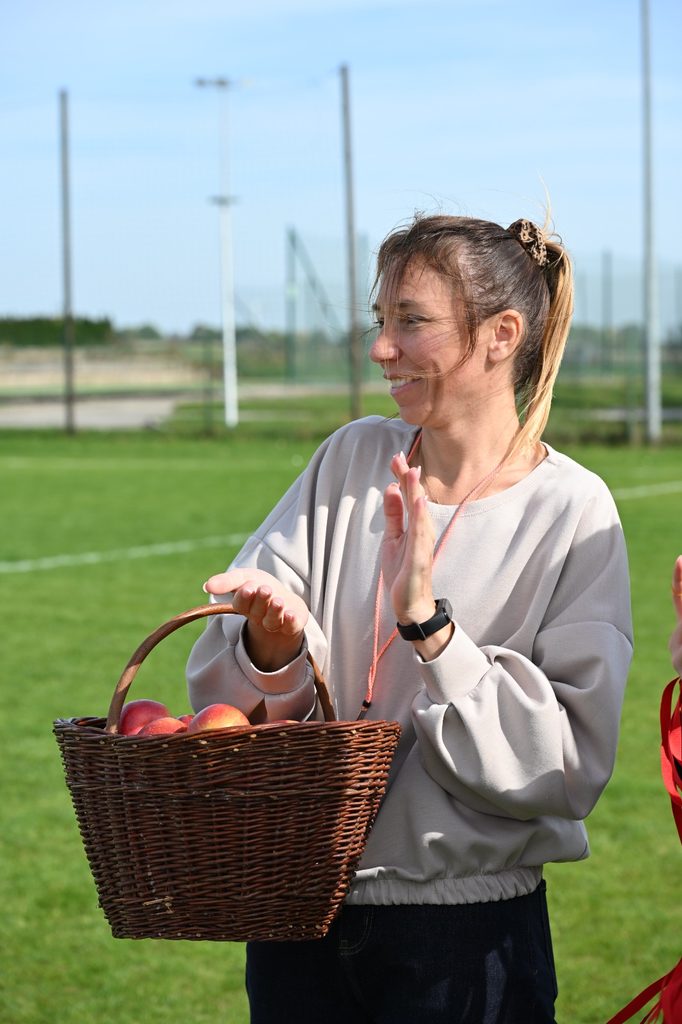 Na zdjęciu widzimy moment zdrowego poczęstunku przygotowanego dla uczestników „Porowej sztafety”. W wiklinowym koszu znajdują się świeże jabłka, które po sportowych zmaganiach trafiły do uczniów jako smaczna i zdrowa przekąska.
