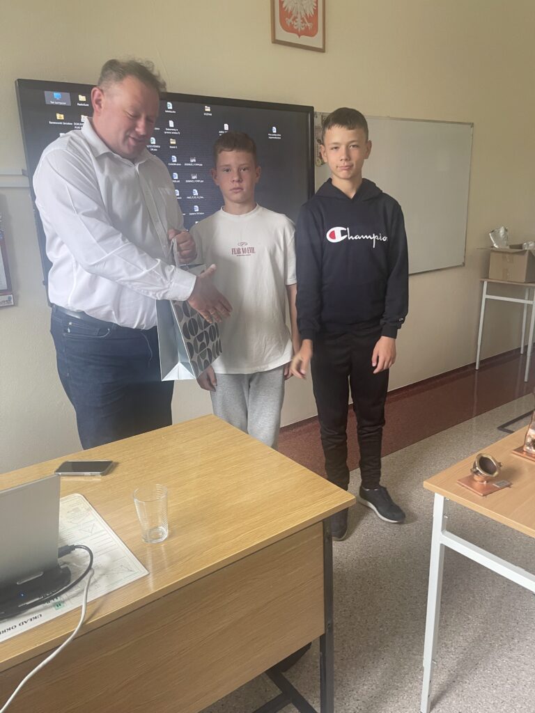 Zdjęcie przedstawia uczniów klas 7 dziękujących za spotkanie pracownikowi Huty.