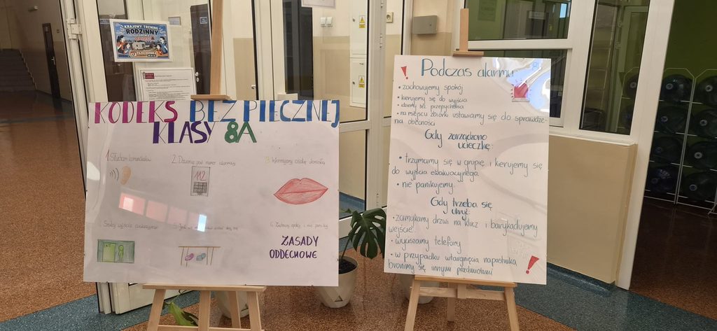 związanych z Krajowym Treningiem Rodzinnym – Akademią Ochrony Ludności i Obrony Cywilnej (OLiOC).
Prace zatytułowane „Kodeks Bezpiecznej Klasy 8A” oraz „Podczas alarmu” prezentują najważniejsze zasady bezpieczeństwa obowiązujące w szkole. Uczniowie zwrócili szczególną uwagę na właściwe zachowanie podczas alarmu, konieczność zachowania spokoju, przestrzeganie poleceń nauczycieli, sprawną ewakuację oraz odpowiedzialność za bezpieczeństwo własne i innych.