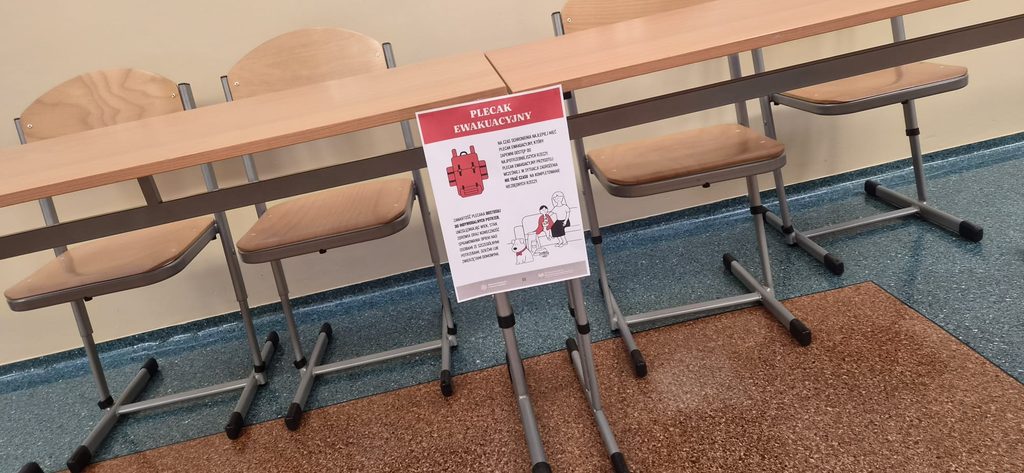 Na zdjęciu przedstawiono materiał edukacyjny dotyczący przygotowania plecaka ewakuacyjnego, zaprezentowany w ramach Krajowego Treningu Rodzinnego – Akademii Ochrony Ludności i Obrony Cywilnej (OLiOC).