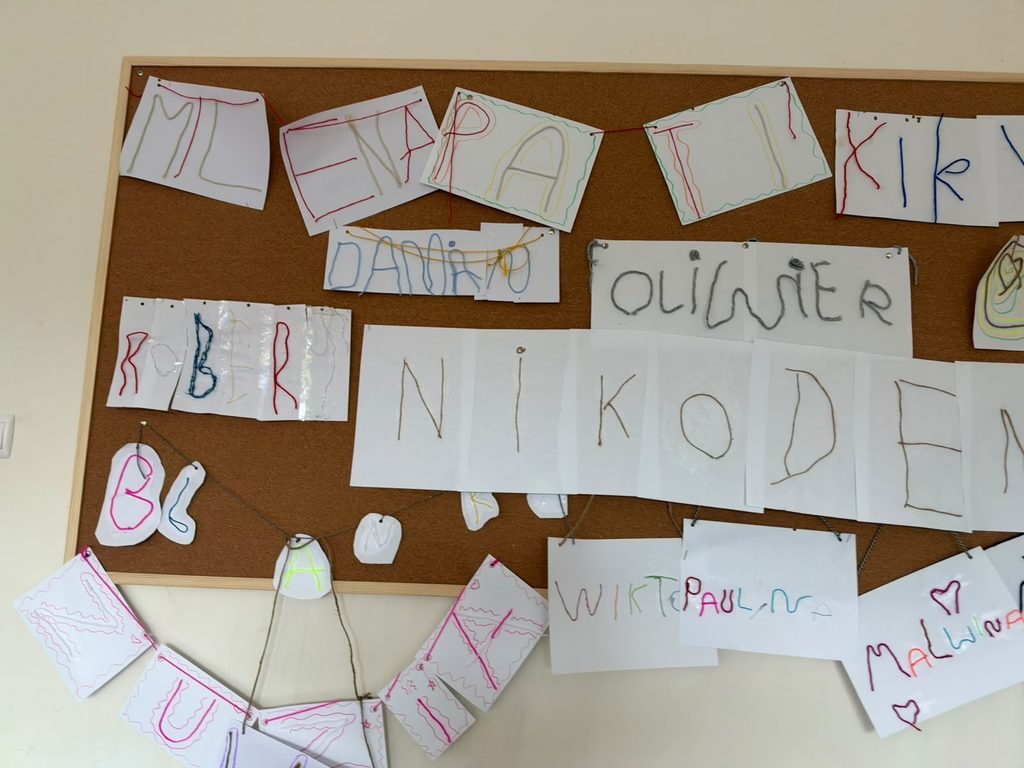 Na zdjęciu widoczne sa kartki, na których uczniowie z wełny i sznurka stworzyli swoje imię.